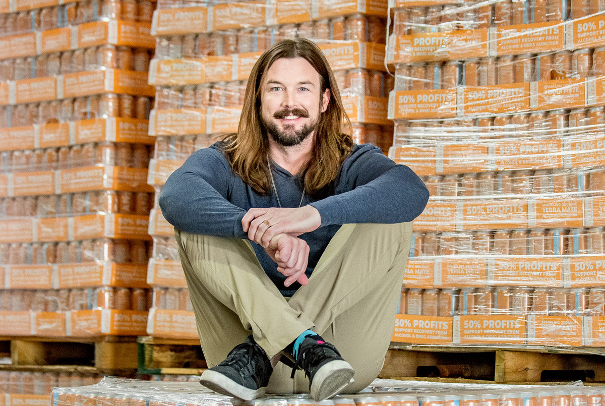 Wes (founder of CLEAN Cause.) sitting in front of pallets of Peach CLEAN cans.